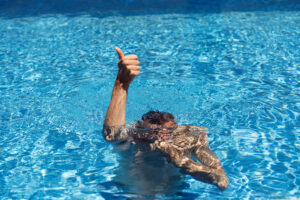 Man chilling under water in pool and showing signs ok with his hand